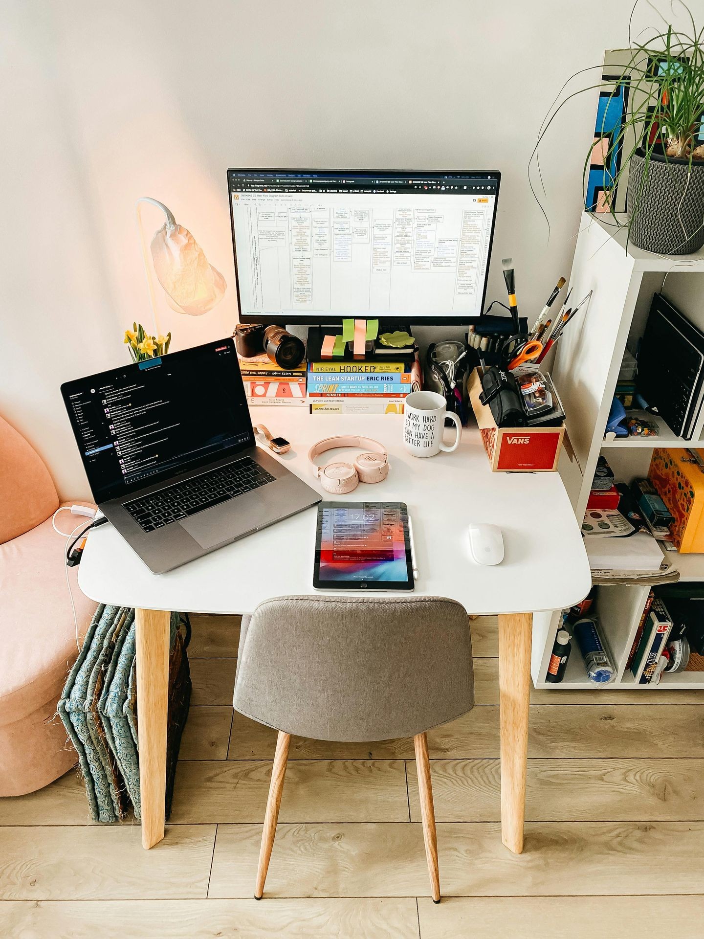 Home office desk with laptop, monitor, tablet, books, and workspace accessories.